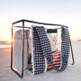 Portable beach shelter with towels and a blanket on a sandy beach at sunset.