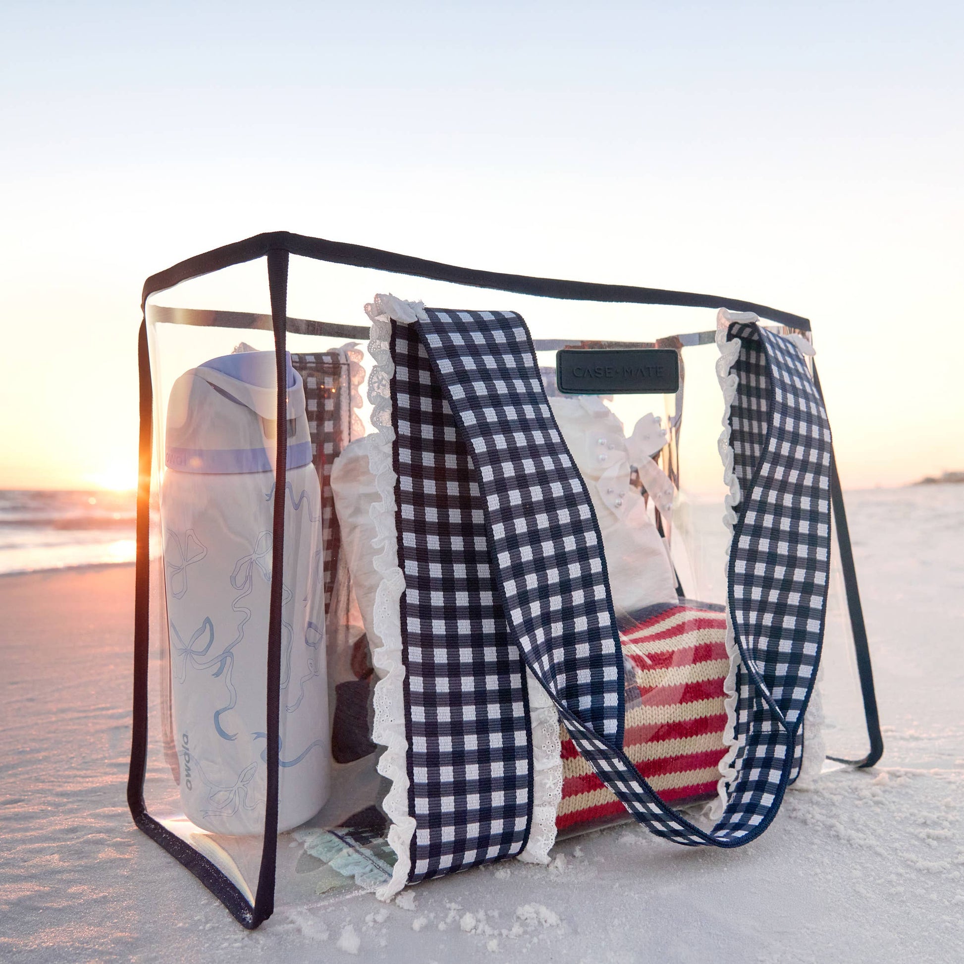 Portable beach shelter with towels and a blanket on a sandy beach at sunset.
