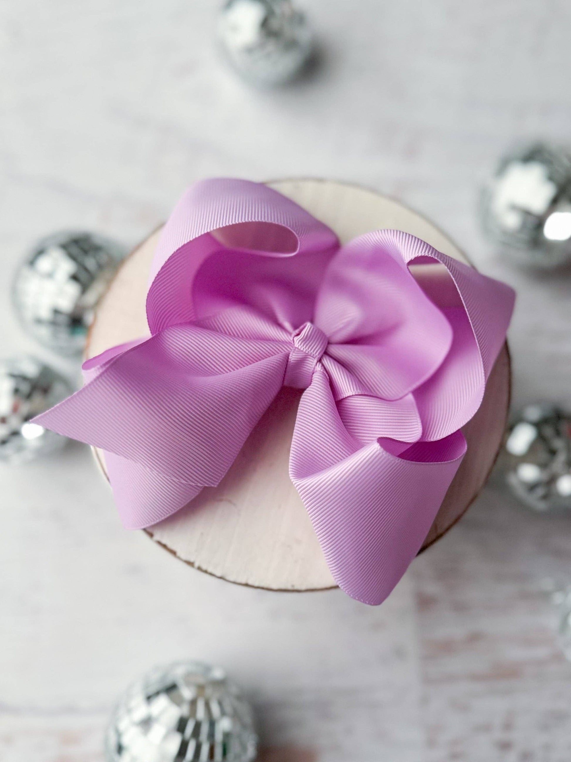 Pink bow on a small round box with silver decorative elements in the background