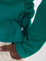 Close-up of a green sweatshirt with a brand logo on a white background