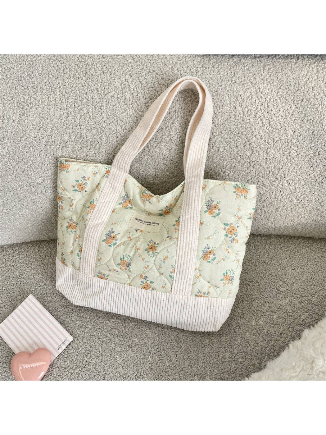 Quilted floral tote bag with light blue flower print front pocket and cream-striped trim