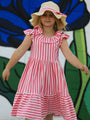 Young girl wearing a red and white striped dress with a sun hat against a colorful background