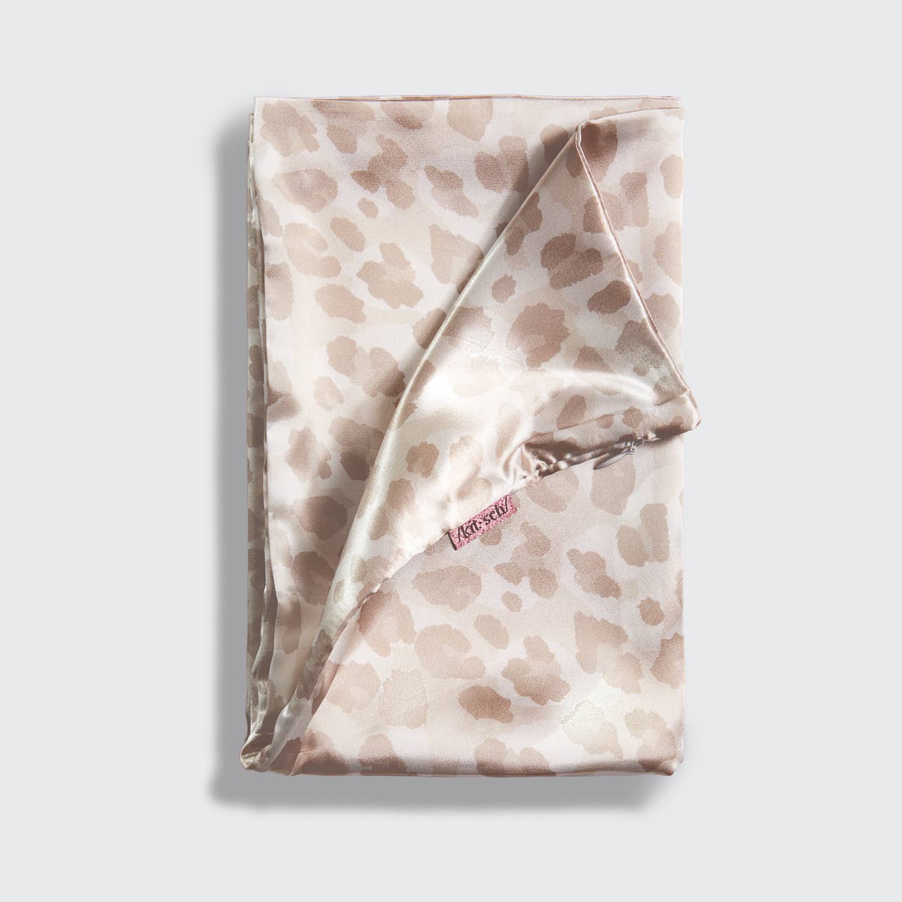 Folded satin scarf with a subtle pattern on a light gray background