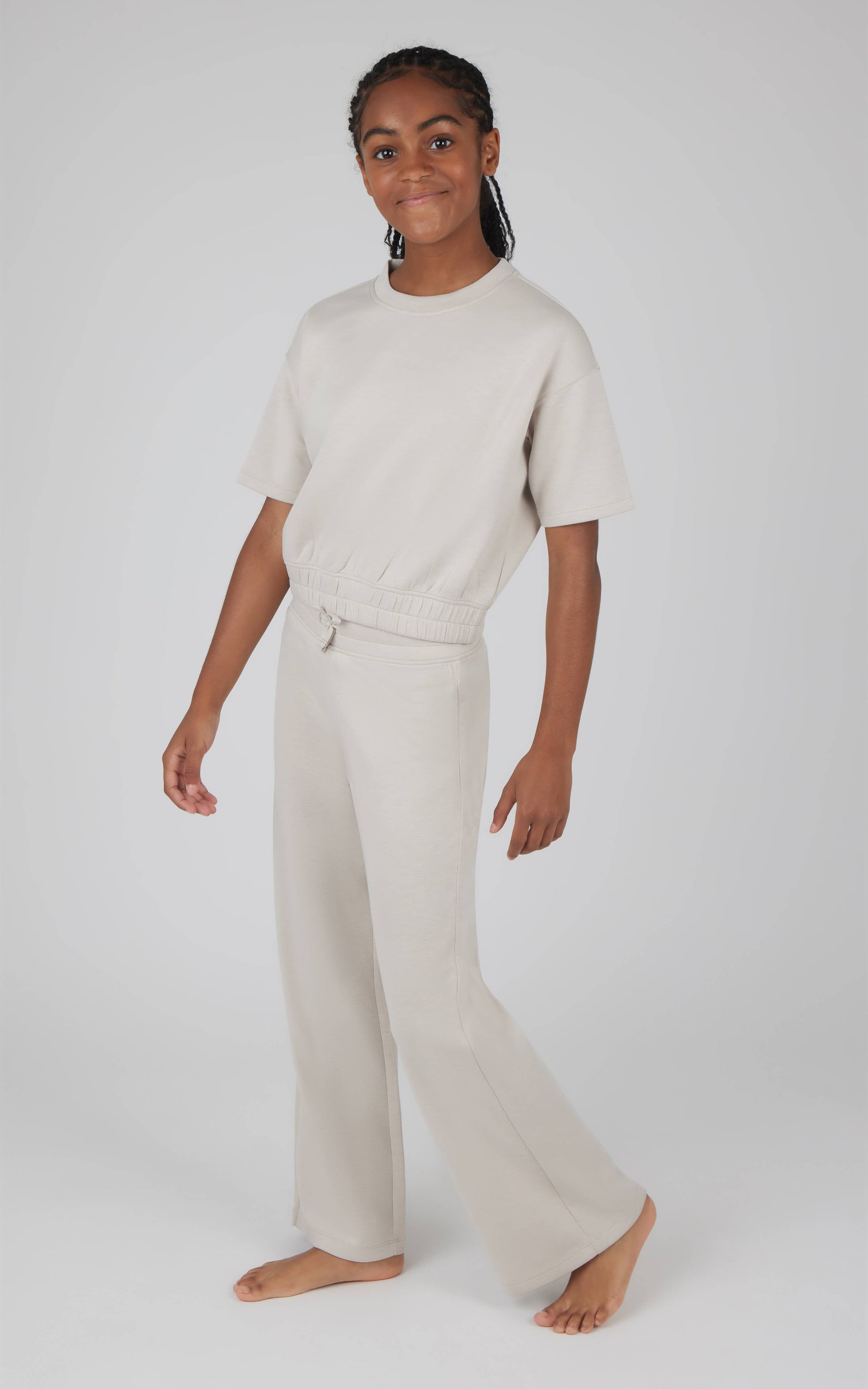 Person wearing a beige sweater and pants on a white background