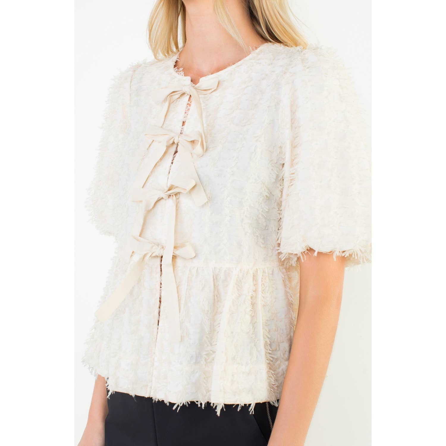 White textured vest with ruffled details worn by a person on a white background