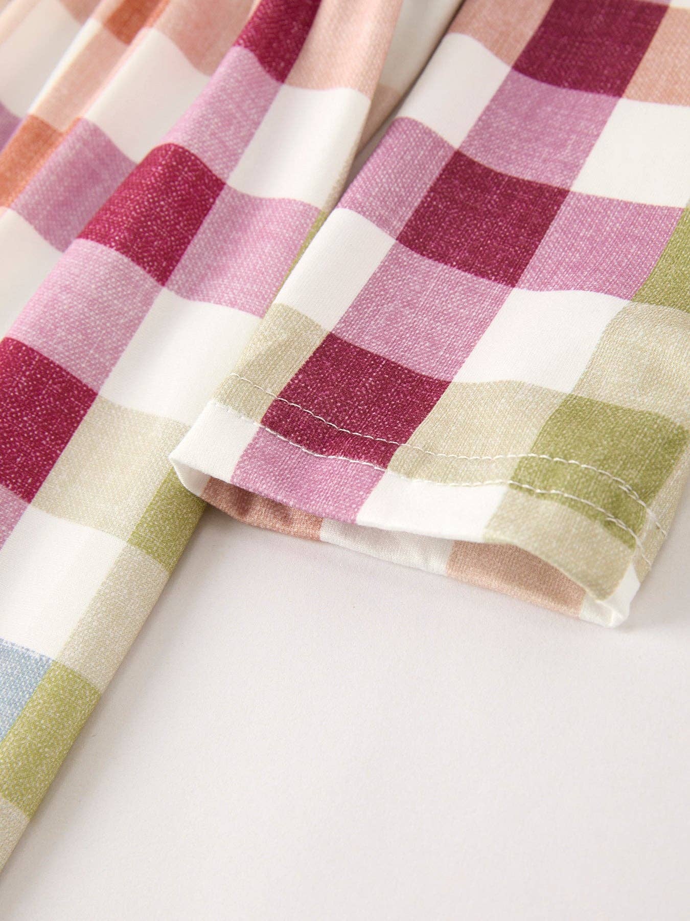 Checkered fabric with pink, green, and white pattern on a white background