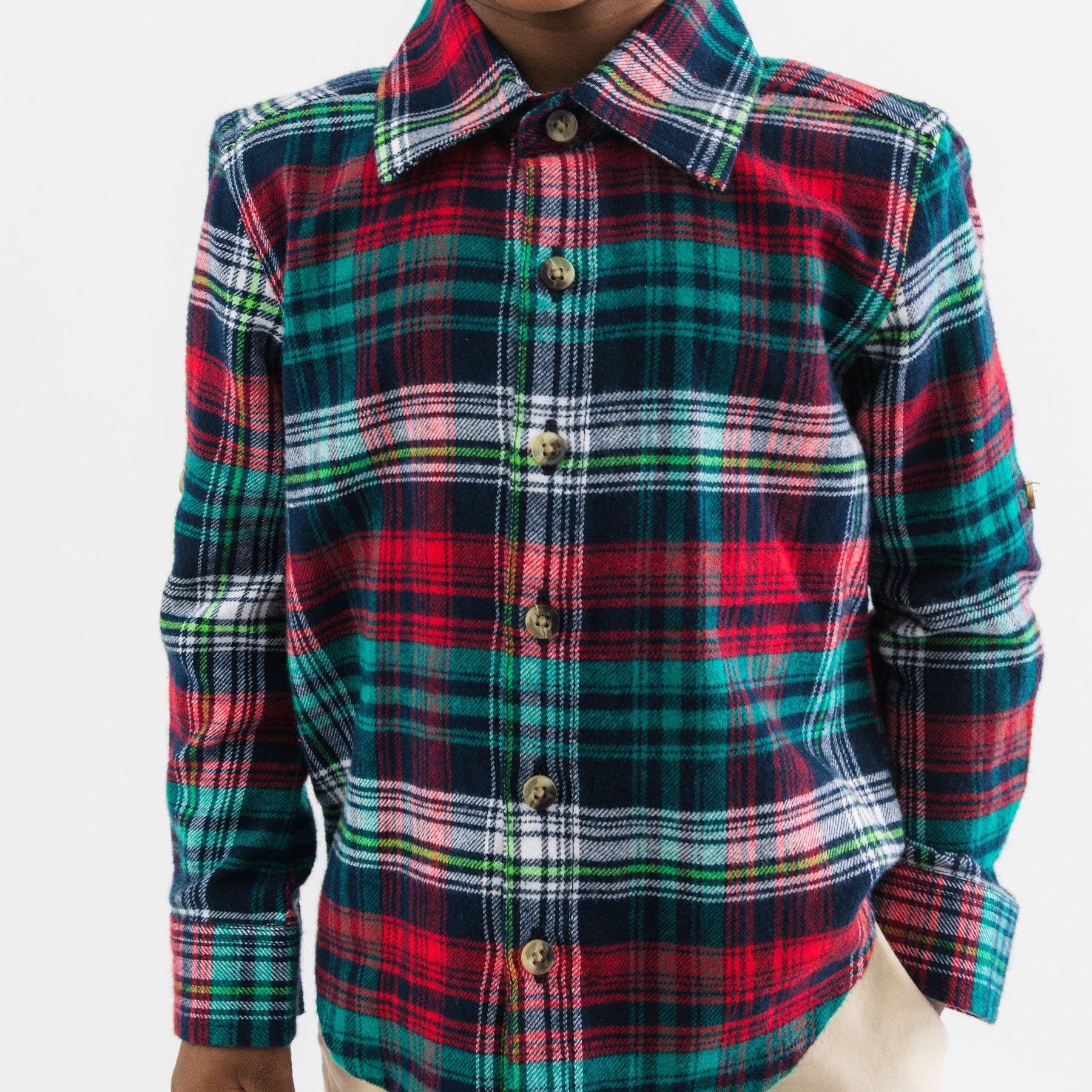 Child wearing a red, green, and blue plaid shirt on a white background