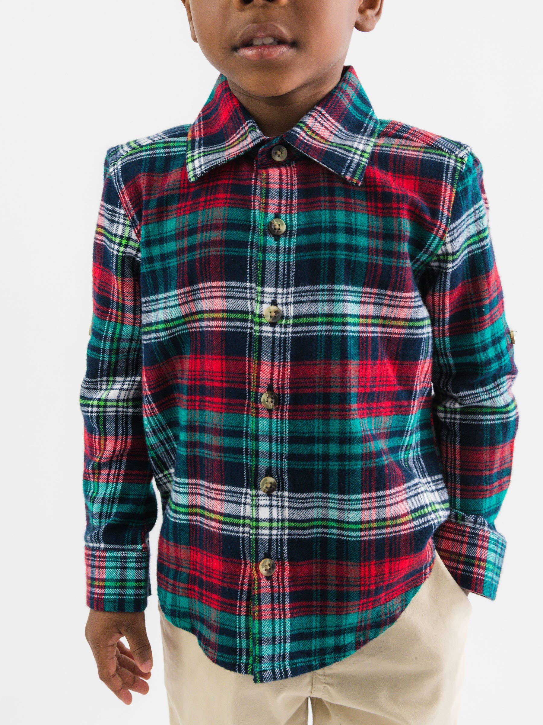 Child wearing a red, green, and blue plaid shirt on a white background