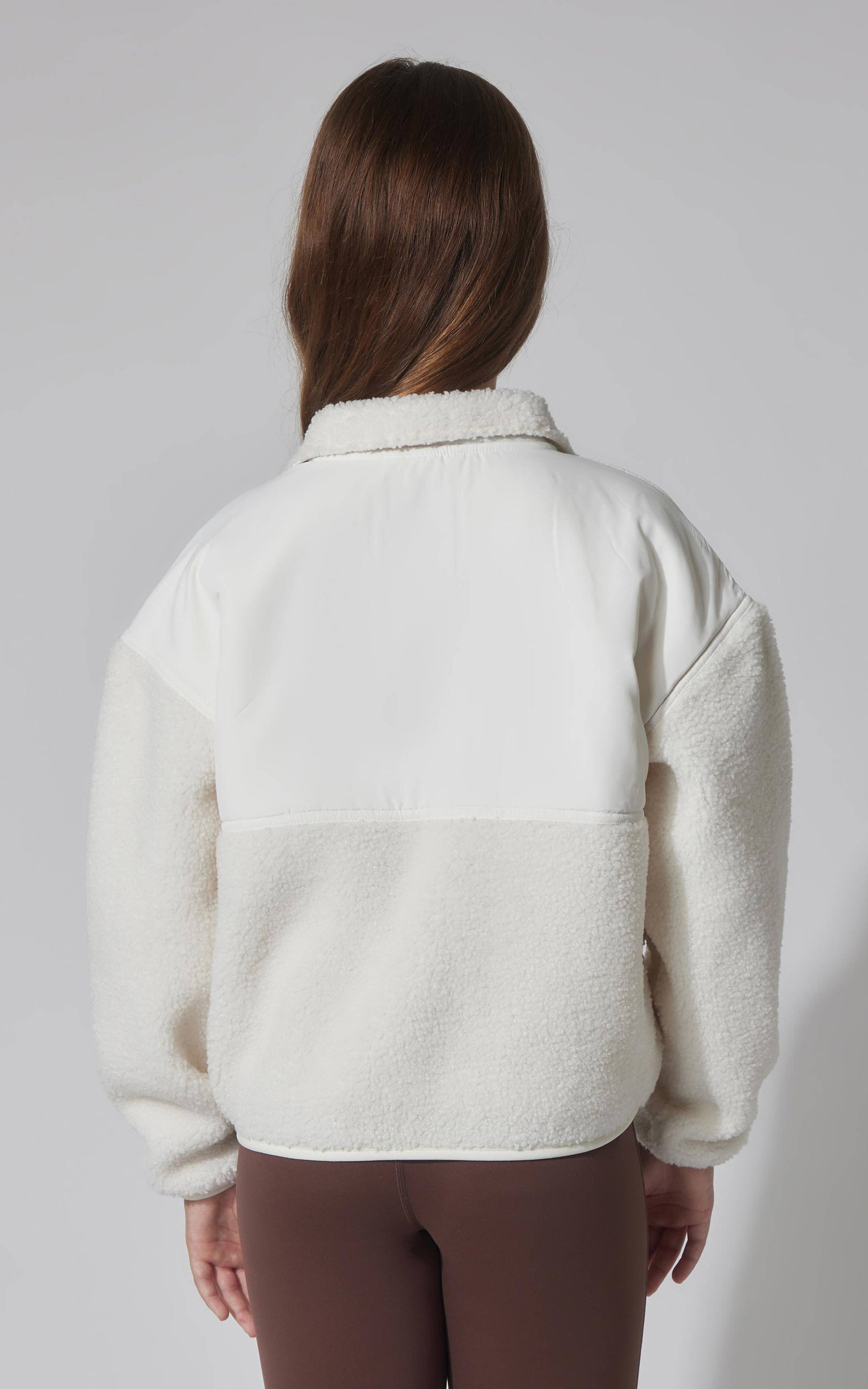 Person wearing a cream-colored fleece jacket on a plain background