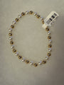 A beaded stretch bracelet featuring alternating white faux pearls and metallic gold beads, with a white barcode tag attached, shown on a textured light gray background.