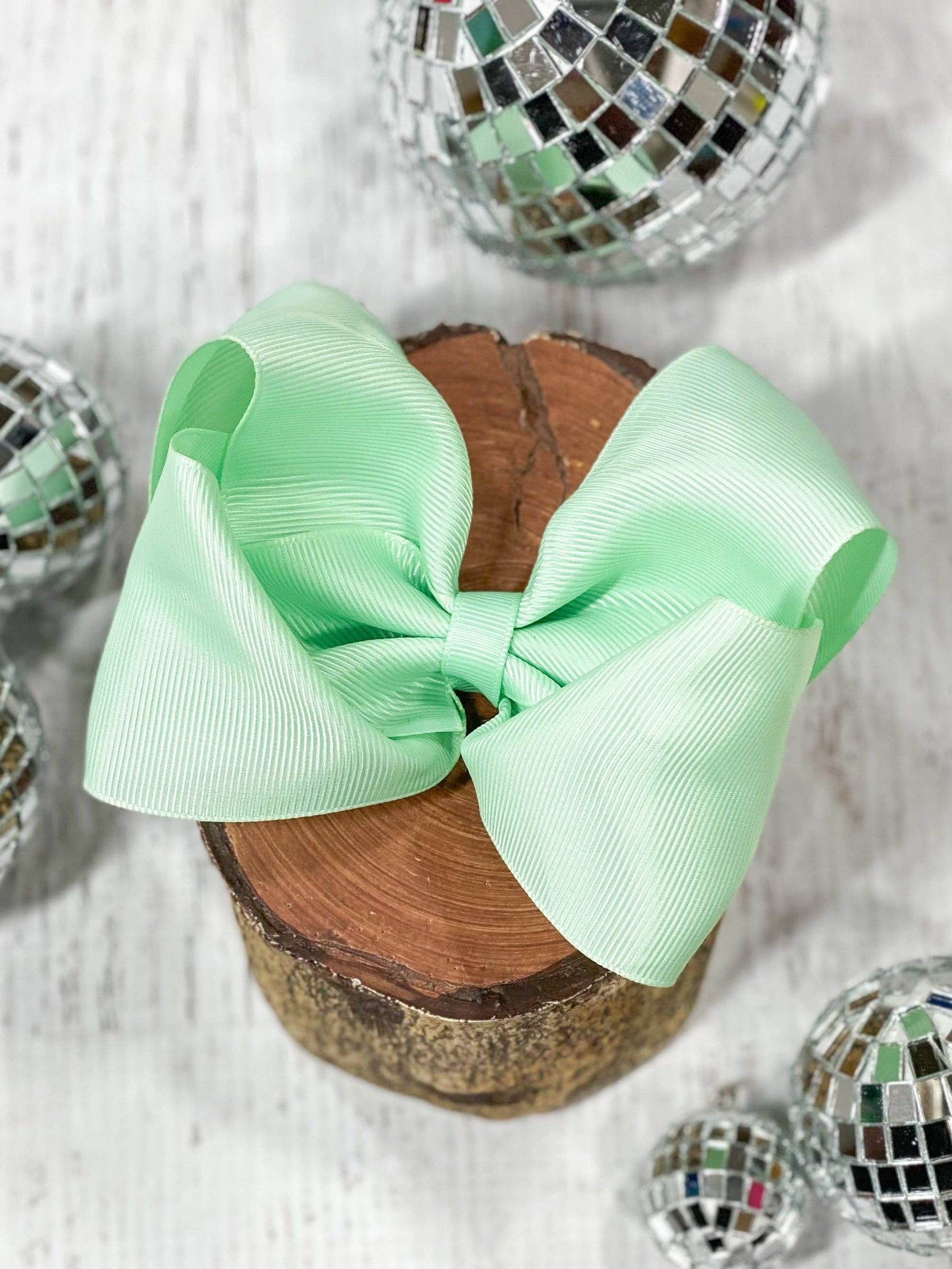 Mint green bow on a wooden block with disco balls in the background