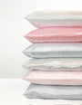 Stack of satin pillowcases in various colors on a white background