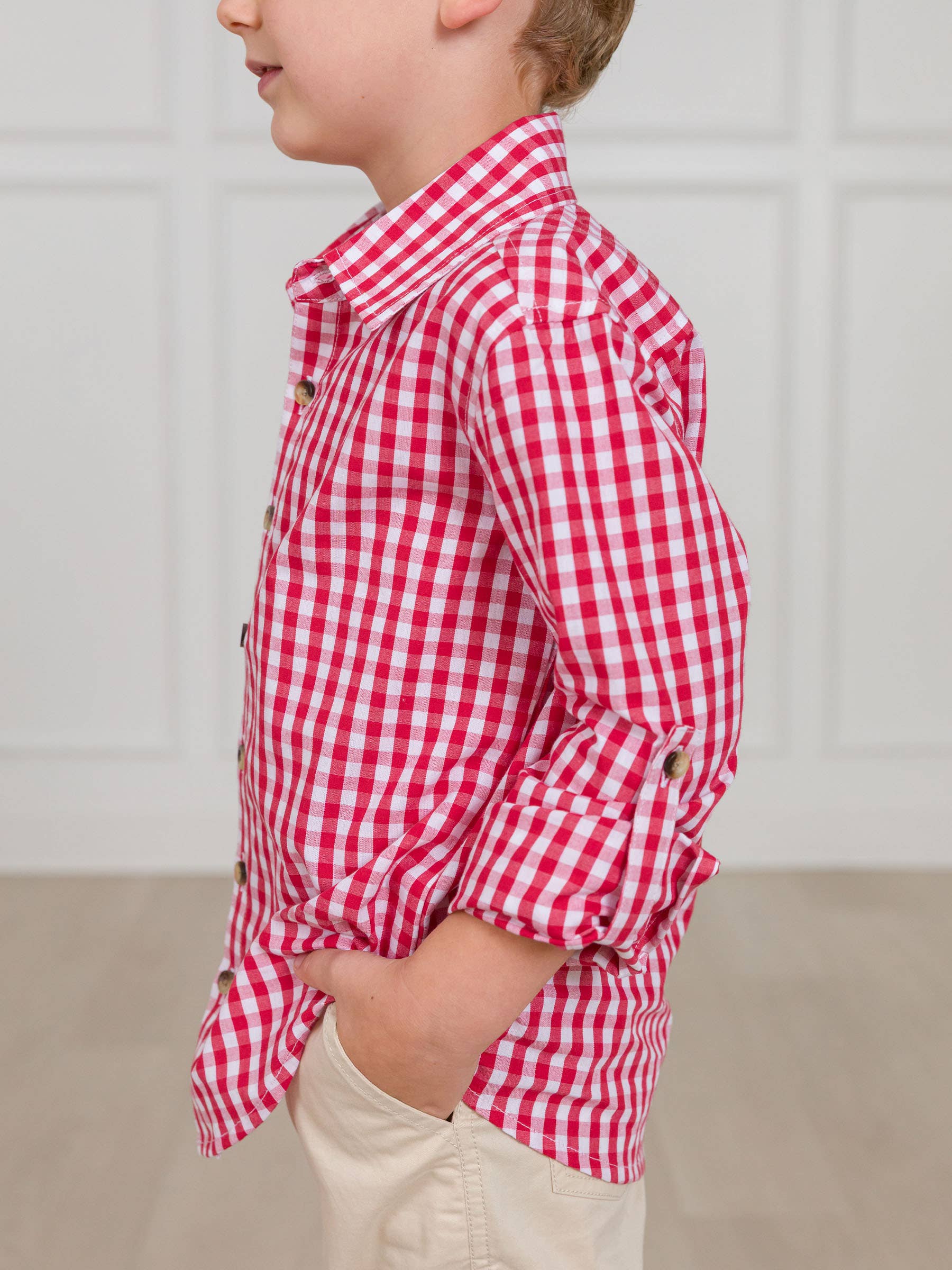 Child wearing a red and white checkered shirt against a neutral background