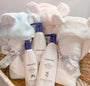 Baby care products including bottles and a towel in a basket with a soft background.