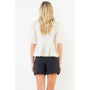 Person wearing a white lace top and black shorts on a white background