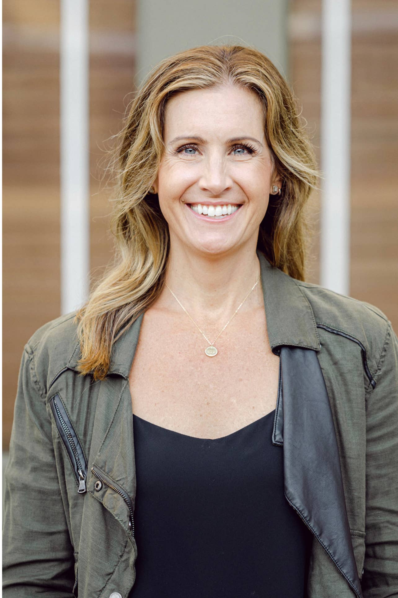 Woman wearing a grey jacket and black top with a blurred background