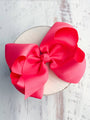 Large pink bow on a white plate with a light wooden background