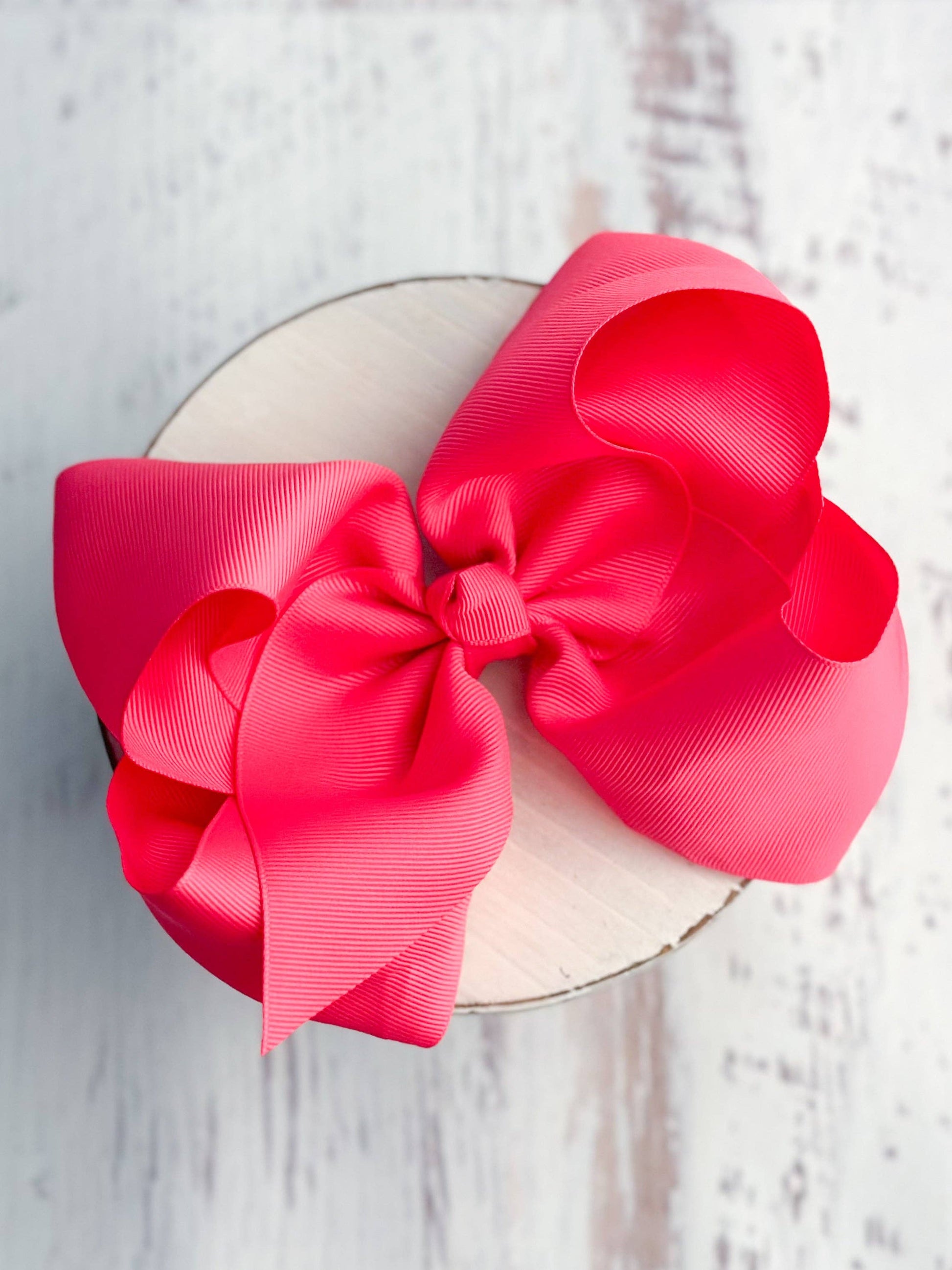 Large pink bow on a white plate with a light wooden background