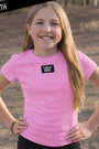 Young girl wearing a pink 'Lulu Mac' t-shirt outdoors.