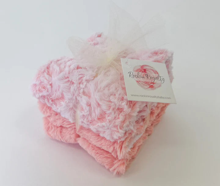 Pink textured baby booties with a brand tag on a white background