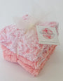 Pink textured baby booties with a brand tag on a white background