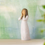White figurine of a woman with long hair against a textured green and blue background