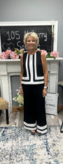 Woman in a black and white outfit standing in a room with a fireplace and decorative items.
