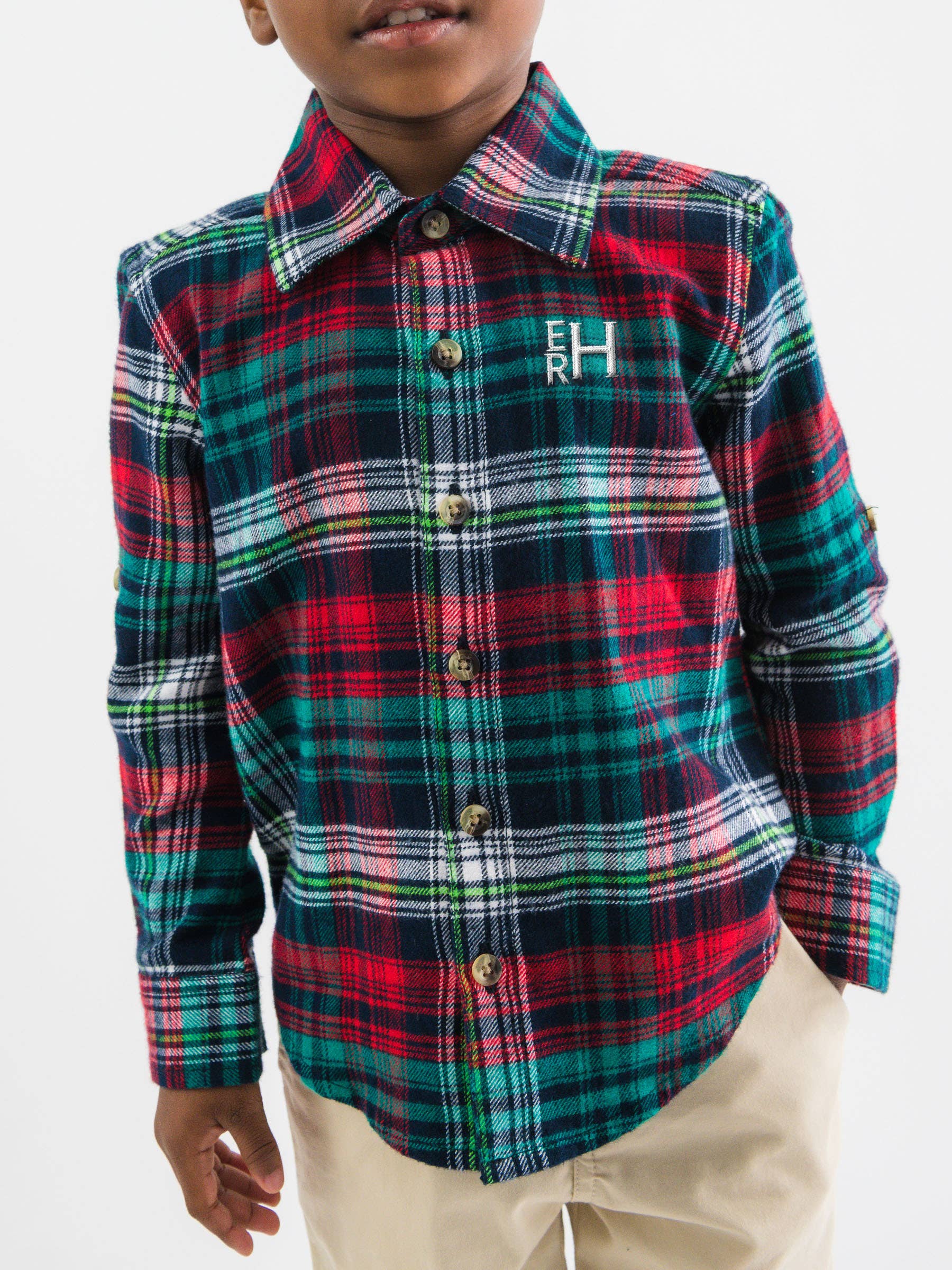 Child wearing a red, green, and blue plaid shirt with a logo on a white background
