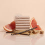 Stack of soap bars with grapefruit slices and vanilla beans on a beige background
