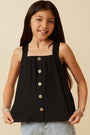 Young girl wearing a black sleeveless top with buttons on a beige background