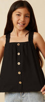 Young girl wearing a black sleeveless top with buttons on a beige background