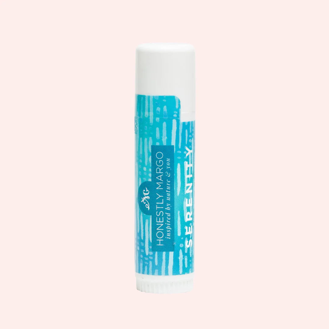Lip balm tube with blue and white design on a light pink background