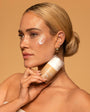 Woman applying foundation to her neck with a beige background