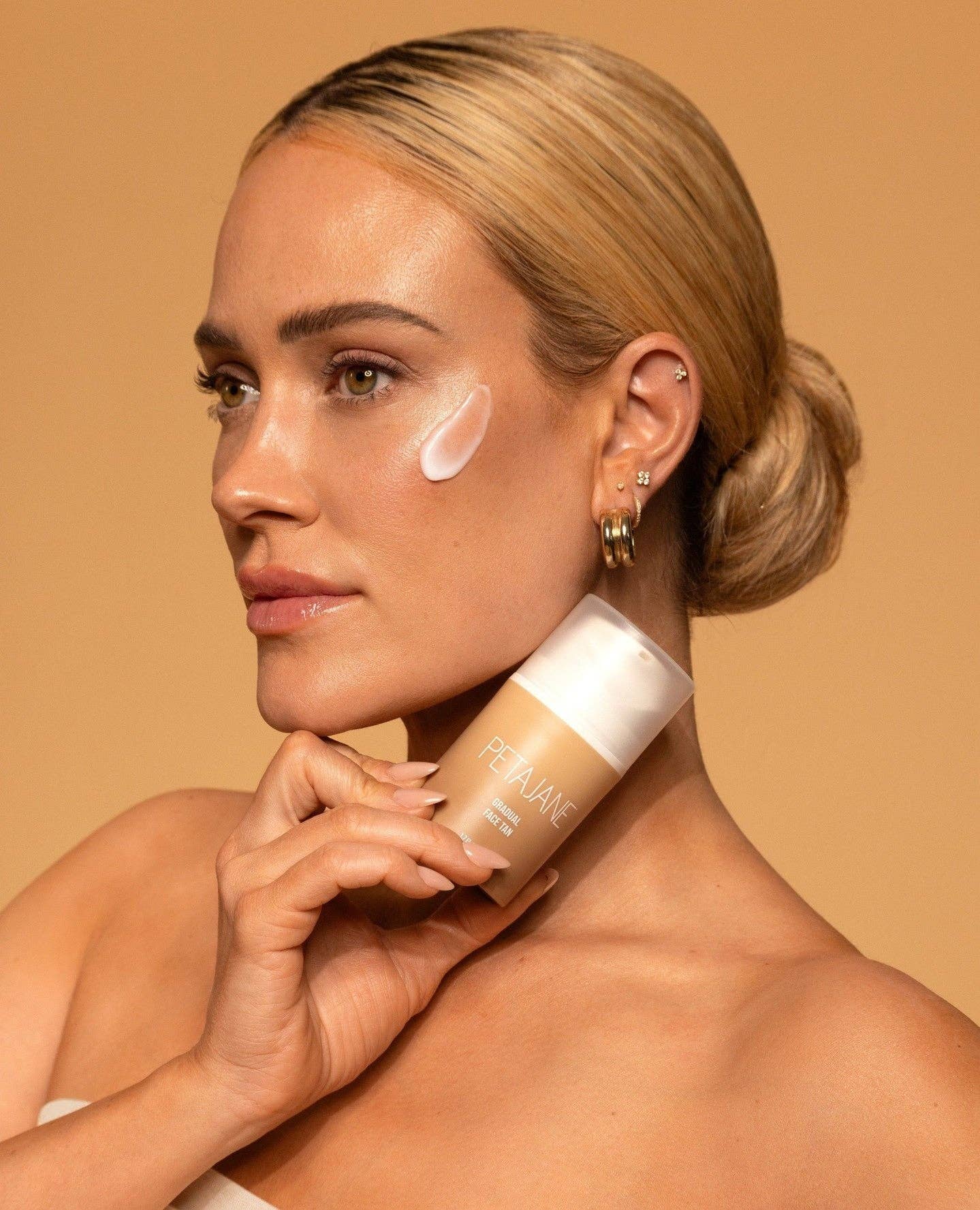 Woman applying foundation to her neck with a beige background