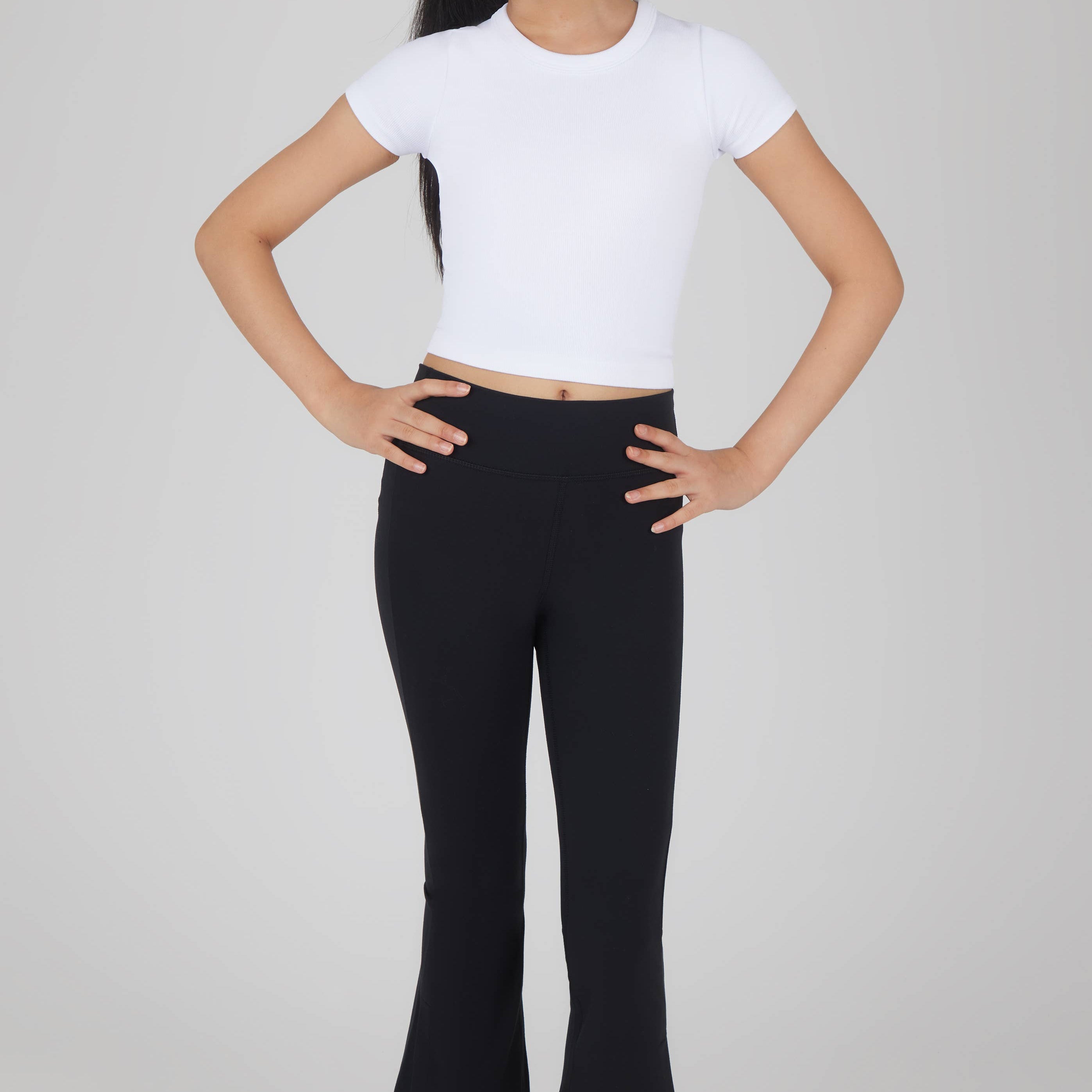 Person wearing a white crop top and black pants on a plain background