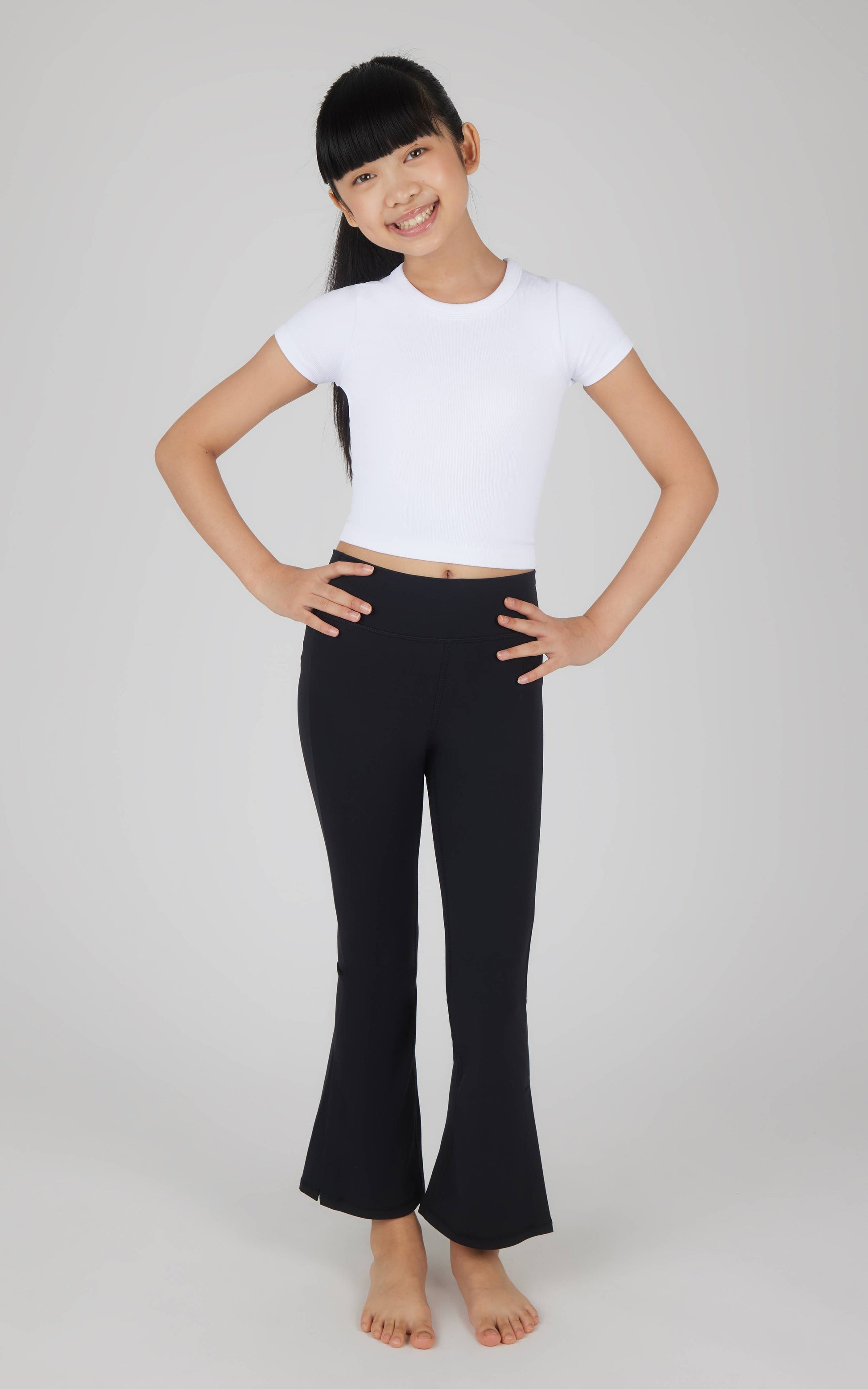Person wearing a white crop top and black pants on a plain background