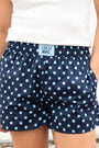 Navy blue shorts with white polka dots worn by a person on a light background