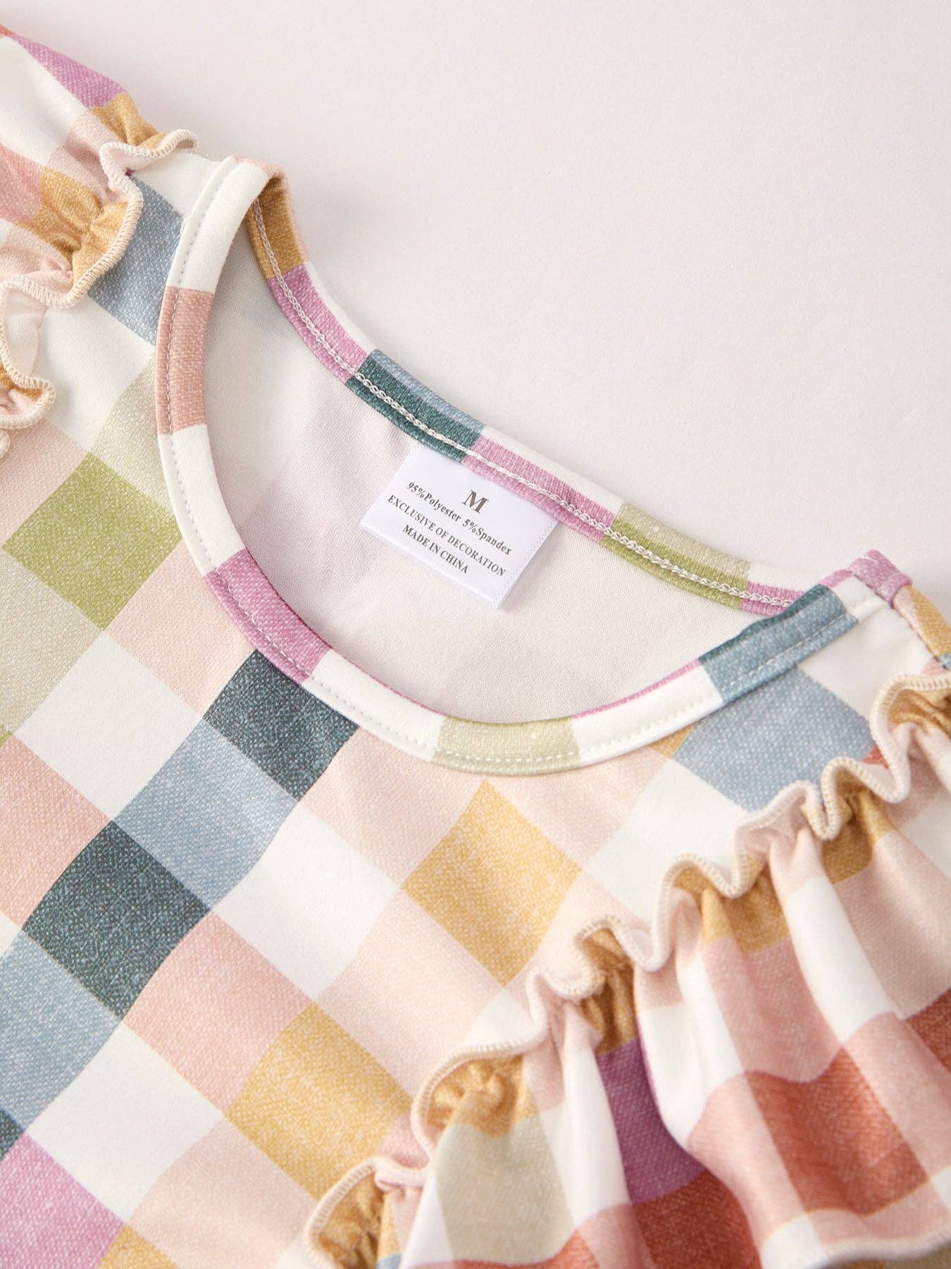 Close-up of a colorful checkered dress with a brand label on a white background