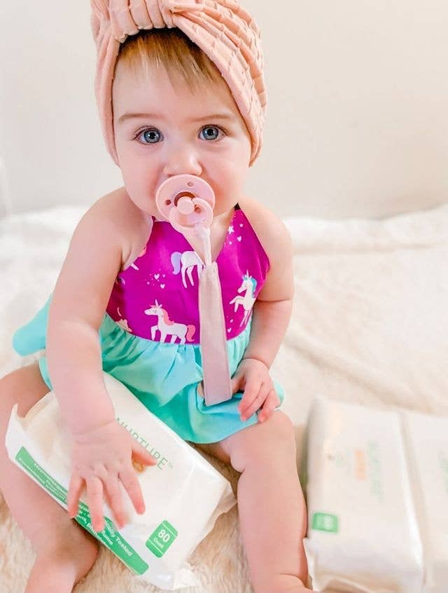 Baby with pacifier wearing a linen clip attached to outfit