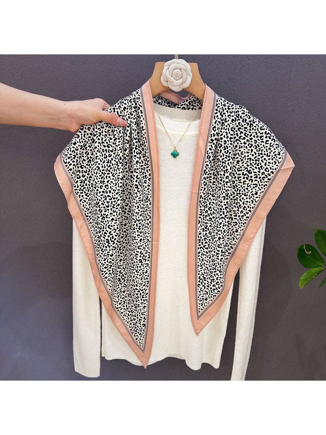 Leopard print bandana with green side trim and peach piping, draped on hanger