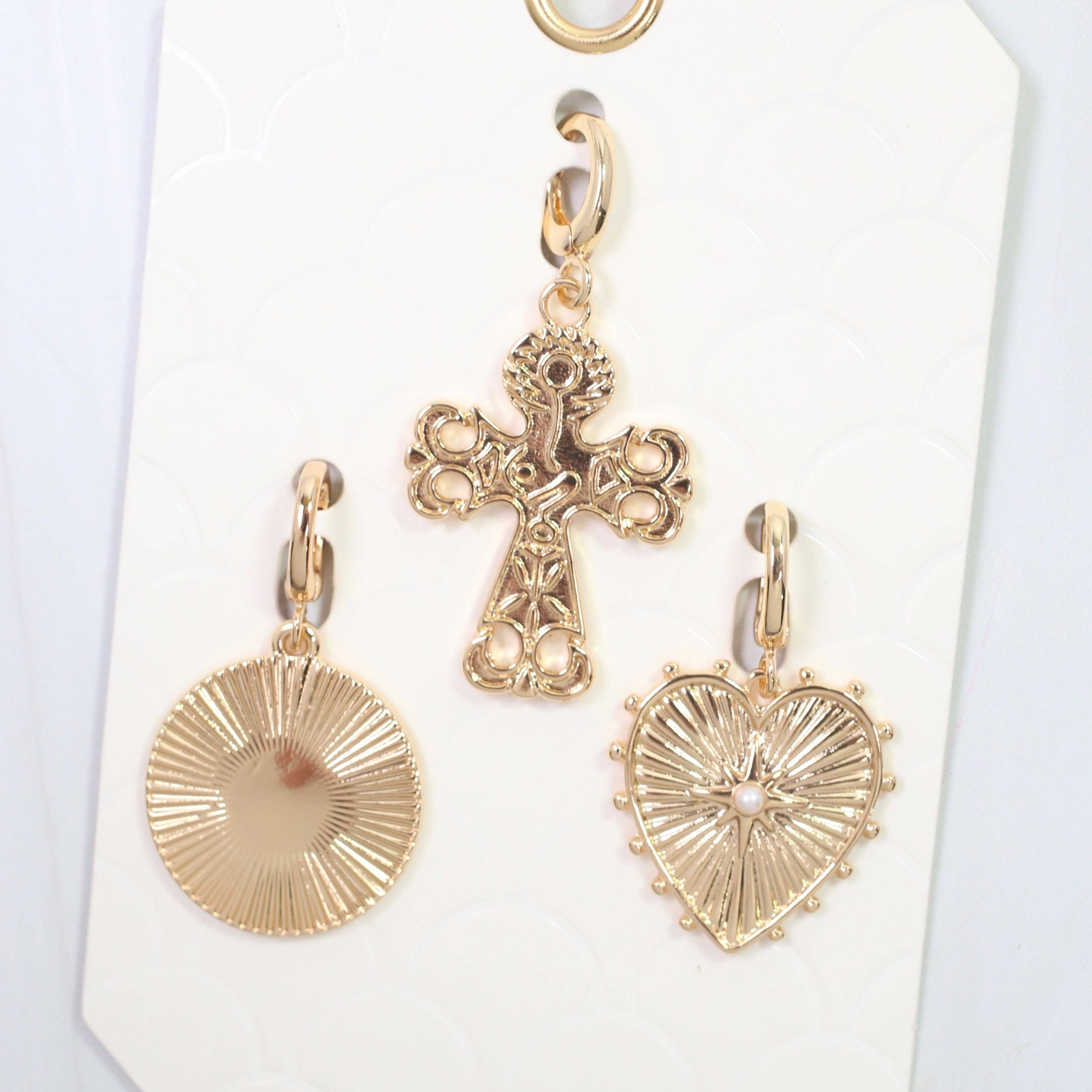 Gold cross and heart-shaped pendants on a white card