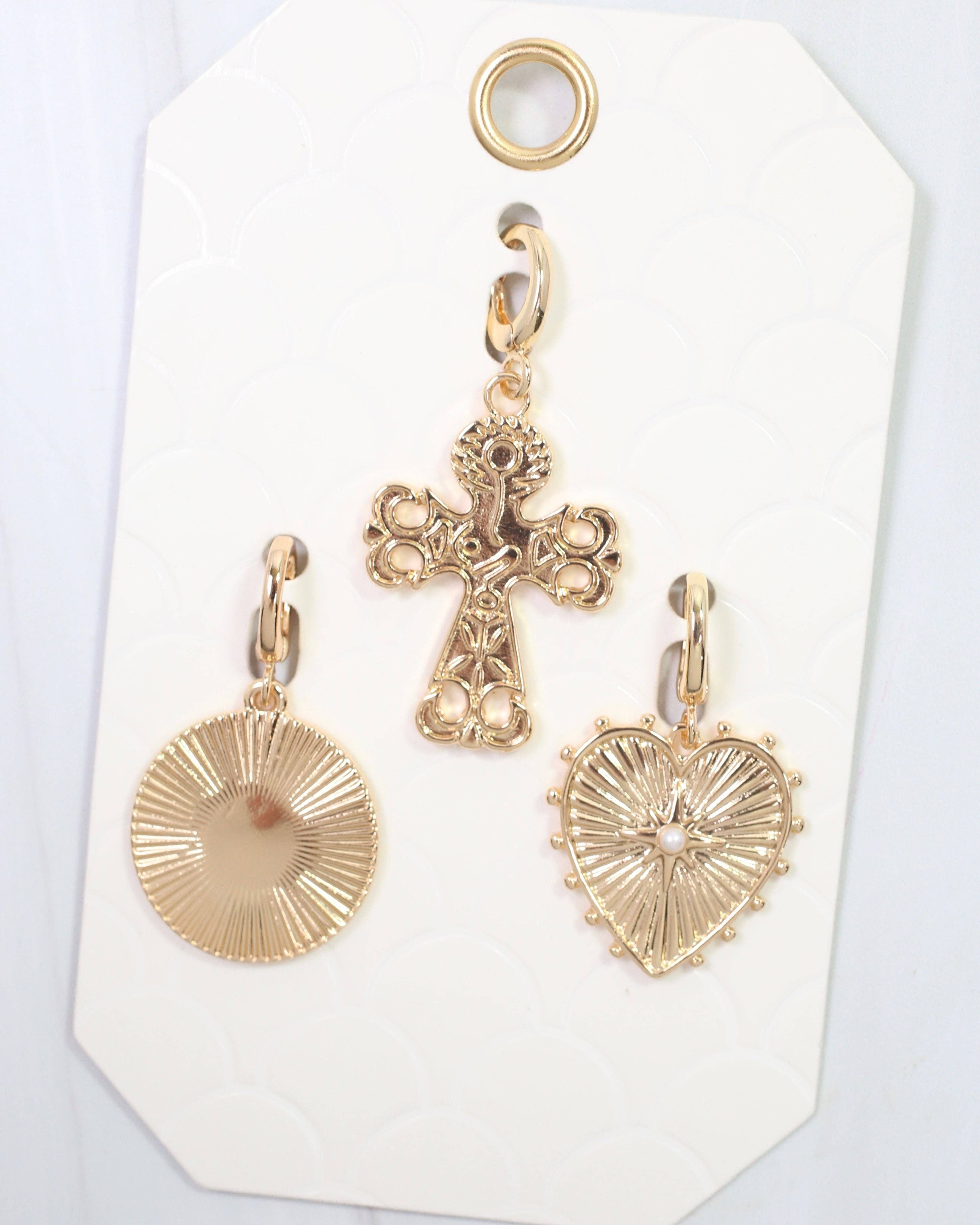 Gold cross and heart-shaped pendants on a white card