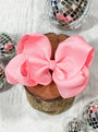 Large pink bow on a wooden block with disco balls in the background