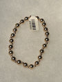 A beaded stretch bracelet made of polished metallic dark gold or rose-gold-toned beads, shown on a light gray textured background with a white product tag attached.