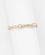 A gold-toned textured bangle bracelet with three white faux-pearl beads, displayed on a clean white background.