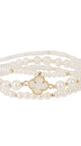 A multi-strand pearl bracelet with a gold-tone clover-shaped charm, displayed on a clean white background.