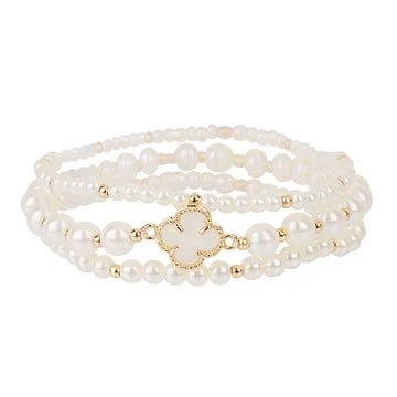 A multi-strand pearl bracelet with a gold-tone clover-shaped charm, displayed on a clean white background.