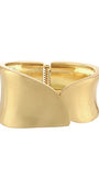 A wide, open cuff bracelet in polished yellow gold, featuring a sculptural, wavy, wing-like design with a textured spring clasp in the center, shown on a plain white background.