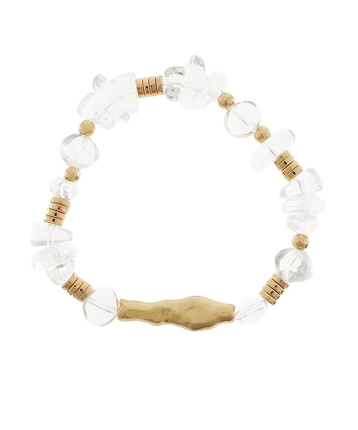 A beaded stretch bracelet featuring clear faceted crystal beads, small tan wooden beads, and a textured gold-toned central charm, displayed on a solid white background.