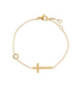 Gold bracelet with a cross and small round charm on a white background